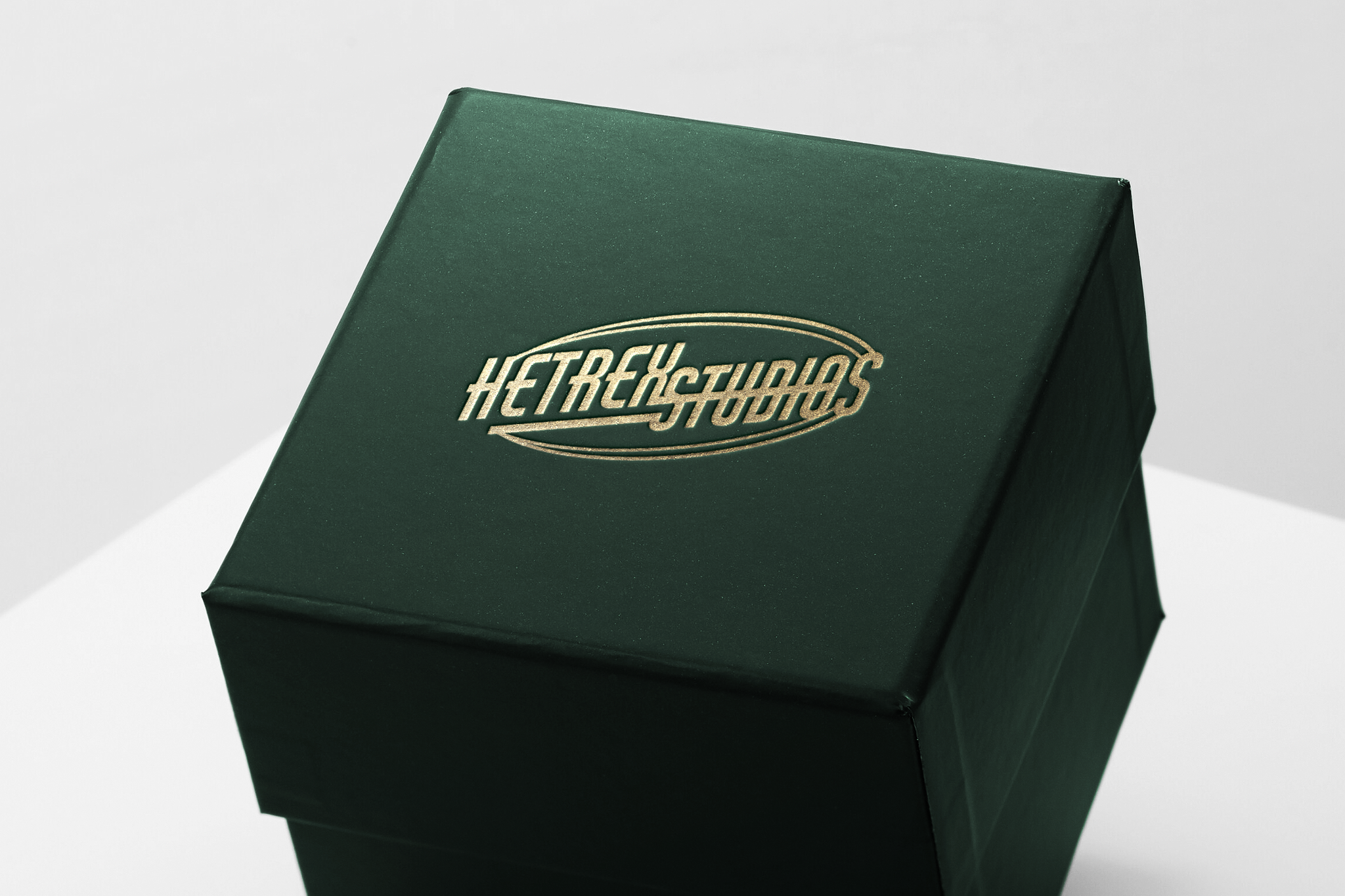 Dunkelgrüne hochwertige Verpackungsbox mit goldgeprägtem Hetrex Studios Logo auf weißem Hintergrund.